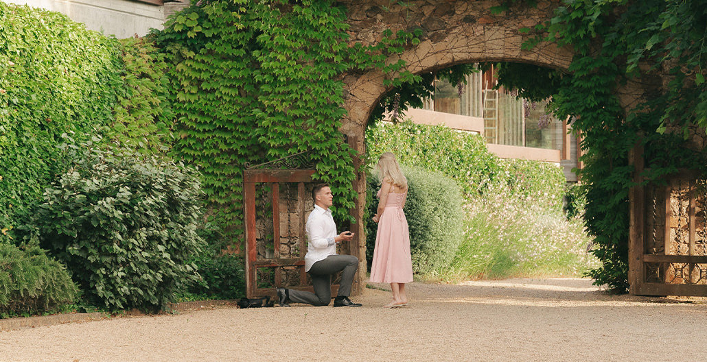 Surprise marriage proposal under an ivy-covered stone arch on the Costa Brava